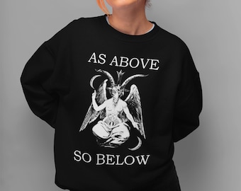 Peut inclure: Un sweat-shirt noir à manches longues avec une impression graphique blanche représentant une figure ailée et cornue en position assise. Le texte "AS ABOVE" est imprimé au-dessus et "SO BELOW" est imprimé en dessous en lettres blanches.