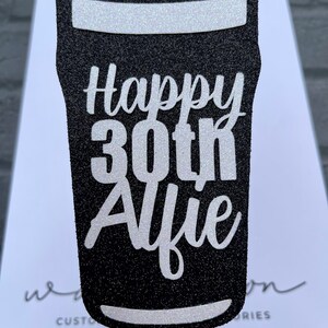 K&ouml;nnte beinhalten: Schwarzer und wei&szlig;er Glitzer-Kuchentopper in Form eines Bierglases mit dem Text "Happy 30th Alfie".