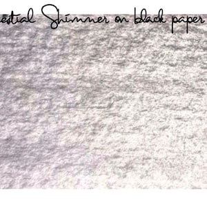 May include: A close-up of a silver shimmery paint applied to black paper. The paint has a textured, metallic look.