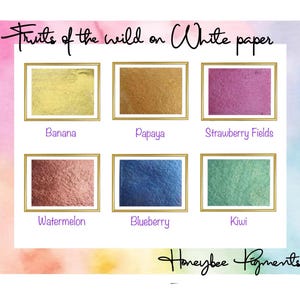 May include: Six small squares of metallic paint swatches on white paper. The swatches are labelled "Banana", "Papaya", "Strawberry Fields", "Watermelon", "Blueberry", and "Kiwi". The text "Fruits of the wild on White paper" is at the top of the image. The text "Honeybee Pigments" is at the bottom of the image.