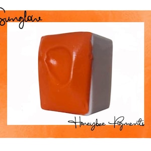 May include: A single, square watercolor pan in a white tray. The pan is a bright orange color. The text "Sunglow" is written in black above the pan. The text "Honeybee Pigments" is written in black below the pan.