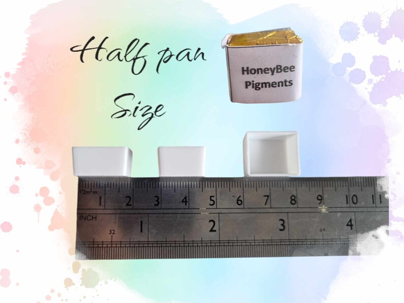 May include: Three white watercolor pans, measuring approximately 2 inches wide, labeled "Half pan Size". A ruler is placed below the pans for size reference. A gold foil wrapped watercolor pan labeled "HoneyBee Pigments" is shown above the pans.