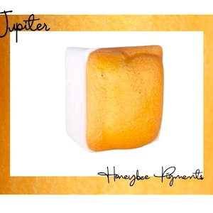 Puede incluir: Una bandeja de pintura cuadrada de color dorado con una etiqueta blanca. La etiqueta dice "Jupiter".