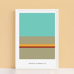 Puede incluir: Una impresión enmarcada con un diseño minimalista que presenta rayas horizontales en tonos turquesa, gris, amarillo y rojo. El texto "asteroid city - wes anderson - 2023" está impreso en la parte inferior de la impresión.