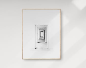 May include: A black and white photograph of a hallway with multiple doorways leading to a vanishing point. The image is framed in a light wood frame.