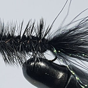 May include: A black fly fishing lure with a long, bushy tail and a smaller, more compact body.