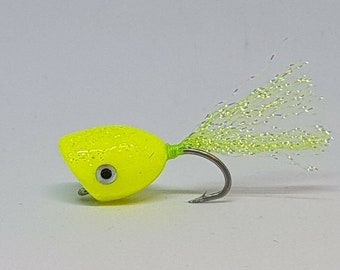 May include: A bright yellow fly fishing lure with a green tail and a black eye.