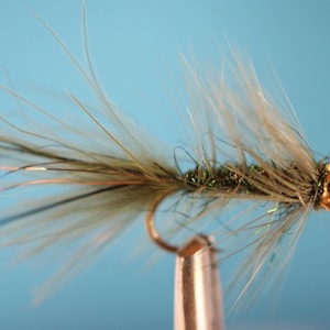May include: A green and gold fly fishing lure with a long, feathery tail.