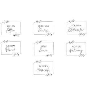 Puede incluir: Un conjunto de siete etiquetas cuadradas en blanco y negro con texto en alemán y bordes florales. Las etiquetas incluyen frases como "Seelen Futter" y "Glücks Momente". El diseño es simple y elegante.