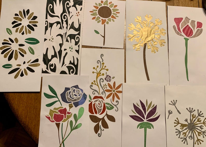 May include: A set of nine stencils featuring various floral designs. The stencils are made of a thin, flexible material and are perfect for creating intricate patterns on walls, furniture, and other surfaces. The designs include a sunflower, a dandelion, a rose, a lotus flower, and a variety of other floral motifs.