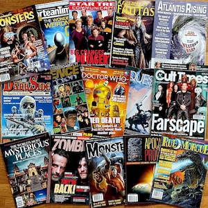 May include: A collection of vintage magazines with various covers featuring science fiction, fantasy, and horror themes. Titles include "Famous Monsters," "Darkside," "Doctor Who," and "Farscape." The magazines are arranged on a wooden surface.