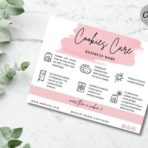 May include: A rectangular white card with a pink brushstroke header titled Cookies Care and Business Name. It features black line icons and text instructions for cookie storage, including freezing and defrosting, with website and social media placeholders.