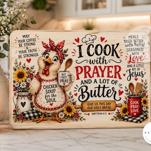 Könnte beinhalten: Ein rechteckiges Holzschneidebrett mit einem Cartoon-Huhn, das ein rotes Kopftuch mit Punkten und eine Schürze trägt. Der Text lautet: I COOK with PRAYER AND A LOT OF Butter, sowie weitere Sprüche wie Chicken Soup for the Soul und Matthew 6:11.