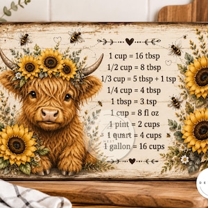 K&ouml;nnte beinhalten: Ein rechteckiges Schild mit einem flauschigen braunen Hochlandrind mit Sonnenblumenkranz, umgeben von Sonnenblumen und Bienen. Das Schild zeigt K&uuml;chen-Umrechnungstabellen, wie 1 cup entspricht 16 tbsp und 1 gallon entspricht 16 cups, in schwarzer Schrift auf hellem Holzmaserungshintergrund.