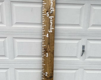 May include: A brown wooden growth chart with white markings and the text "The Smith family" in white cursive lettering.