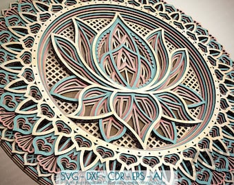 Può includere: Un design di mandala a più strati con un fiore di loto al centro. Il design è realizzato in legno e presenta dettagli intricati in tonalità di marrone, rosa e blu.