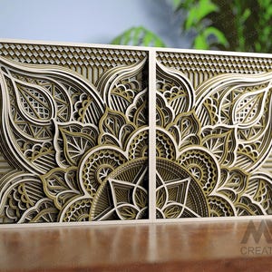 Pode incluir: Uma obra de arte de parede de madeira de dois painéis com um design de mandala em camadas. A obra de arte apresenta padrões intrincados em tons de bege, verde-oliva e branco, com uma borda geométrica. O texto "MW Creations" é visível.