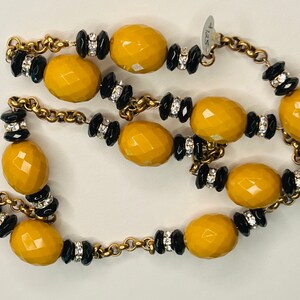 May include: A gold chain necklace with large yellow faceted beads and smaller black beads with rhinestones.
