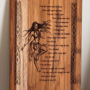 Może przedstawiać: Drewniana deska do krojenia o prostokątnym kształcie i zaokrąglonych rogach. Deska posiada grawerowany wizerunek tańczącej kobiety i tekst. Tekst to wiersz z inspirującymi frazami. Ozdobne wzory znajdują się po bokach.