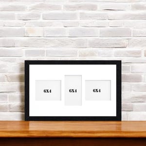 Pode incluir: Moldura de fotos preta com três aberturas de 6x4 polegadas. A moldura está sobre uma superfície de madeira.