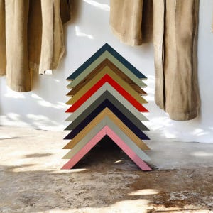 May include: A stack of ten picture frames in various colors, including pink, gray, blue, red, and brown. The frames are arranged in a pyramid shape, with the largest frame at the bottom and the smallest frame at the top.
