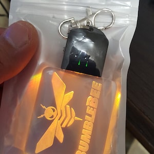May include: A yellow and orange light-up keychain with a bee and the word "BUMBLEBEE" on it.