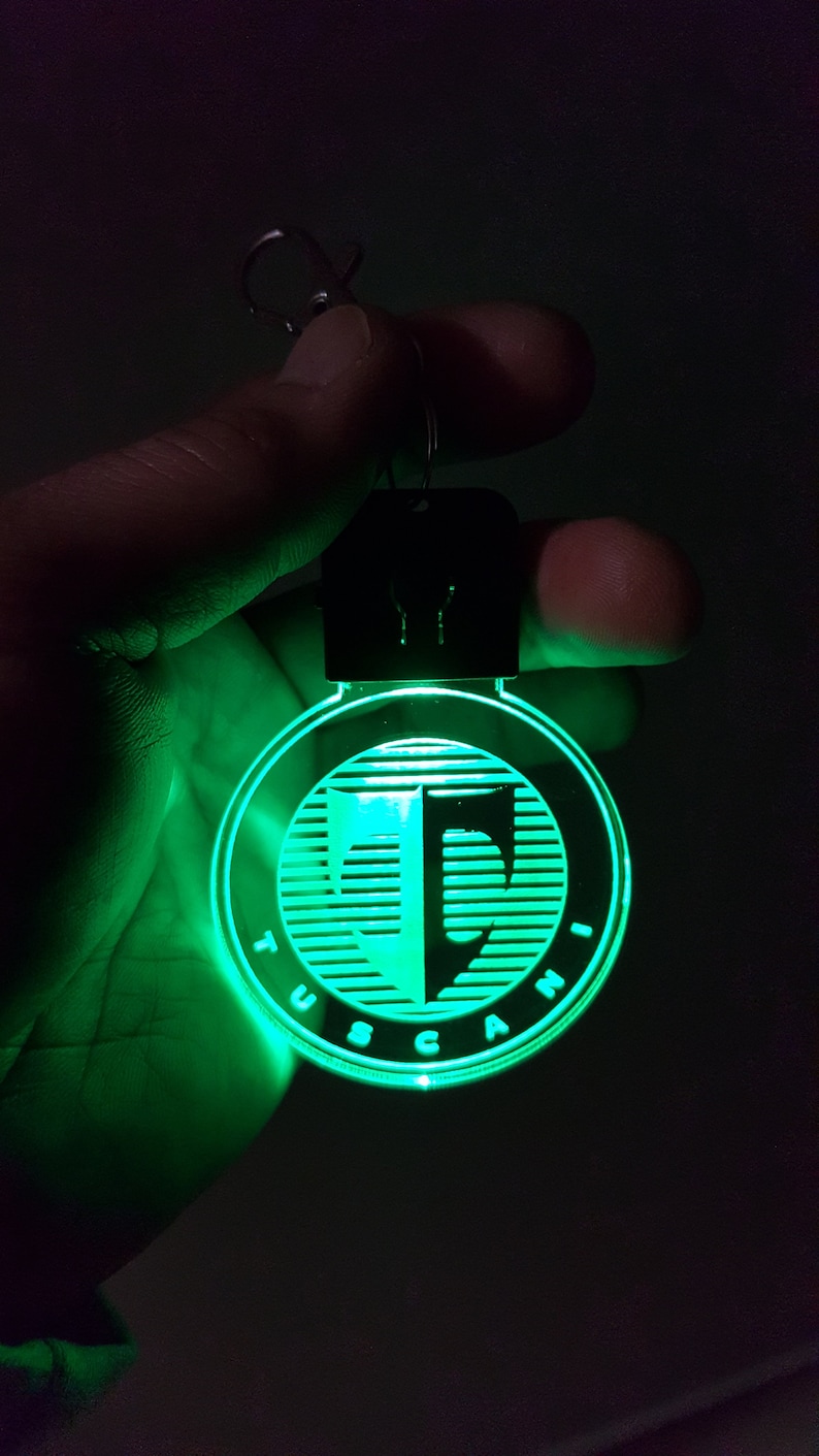 May include: A green glowing keychain with the word "TUSCANI" and a stylized letter "T" inside a circle.