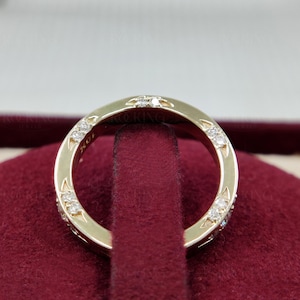 Puede incluir: Un anillo de oro con varias piedras peque&ntilde;as, claras y de corte redondo incrustadas en la superficie met&aacute;lica. El interior del anillo tiene grabado claramente el texto 10K, que indica la pureza del oro de la pieza.