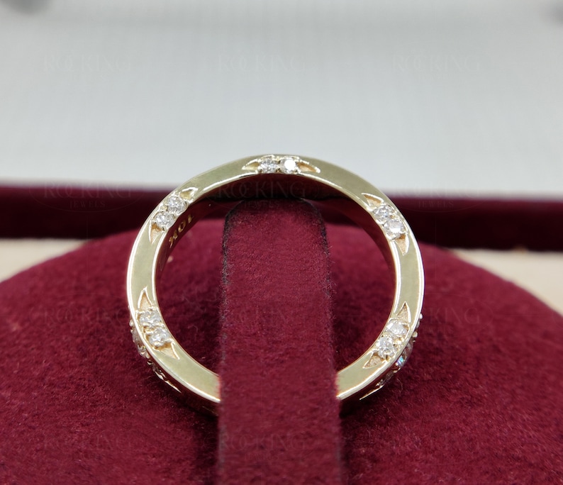 Puede incluir: Un anillo de oro con varias piedras peque&ntilde;as, claras y de corte redondo incrustadas en la superficie met&aacute;lica. El interior del anillo tiene grabado claramente el texto 10K, que indica la pureza del oro de la pieza.