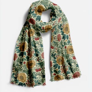 May include: A rectangular scarf with a floral pattern featuring sunflowers, red berries, and green leaves on an off-white background. The scarf has fringed edges and is made of a soft, flowing fabric. The design is reminiscent of vintage botanical illustrations.