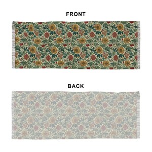 May include: Rectangular floral patterned rug with a cream background. The front side features a repeating pattern of sunflowers, red flowers, and green leaves. The back side has a muted floral design. The rug has fringed edges.