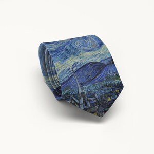 K&ouml;nnte beinhalten: Eine gefaltete Krawatte mit einem Druck von Vincent van Goghs Gem&auml;lde "Sternennacht". Die Krawatte zeigt den wirbelnden blauen Himmel, das Dorf und die Zypressen. Ein klassisches Accessoire f&uuml;r formelle oder halbformelle Kleidung.