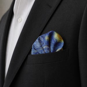 K&ouml;nnte beinhalten: Ein marineblaues Einstecktuch mit einem Druck von Van Goghs Gem&auml;lde "Sternennacht", sichtbar in der Brusttasche eines schwarzen Anzugs. Das Einstecktuch hat wirbelnde blaue, gelbe und wei&szlig;e Farben.