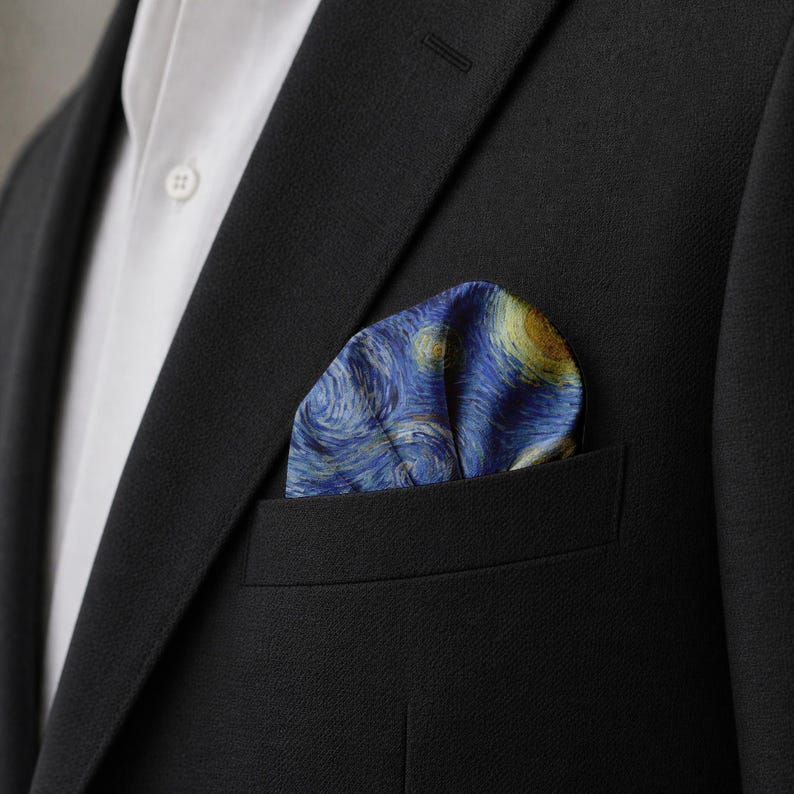 K&ouml;nnte beinhalten: Ein marineblaues Einstecktuch mit einem Druck von Van Goghs Gem&auml;lde "Sternennacht", sichtbar in der Brusttasche eines schwarzen Anzugs. Das Einstecktuch hat wirbelnde blaue, gelbe und wei&szlig;e Farben.