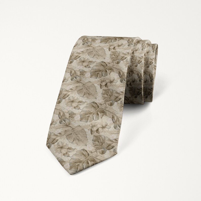 May include: A rolled-up necktie featuring a repeating pattern of beige-colored tropical leaves and flowers. The tie is a neutral color, with a subtle sheen, and is suitable for formal or semi-formal occasions.