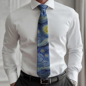 K&ouml;nnte beinhalten: Eine blaue Krawatte mit einem Druck von Van Goghs "Sternennacht". Die Krawatte wird &uuml;ber einem wei&szlig;en Hemd und einer dunklen Hose getragen. Das Kunstwerk zeigt wirbelnde Pinselstriche, einen gelben Mond und Sterne.