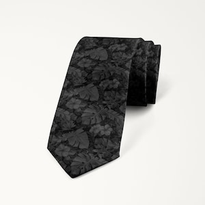 May include: A black tie with a dark gray floral pattern. The pattern features leaves and flowers.