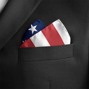 Puede incluir: Un pa&ntilde;uelo de bolsillo doblado con un dise&ntilde;o de bandera estadounidense roja, blanca y azul. El pa&ntilde;uelo de bolsillo est&aacute; en el bolsillo de la chaqueta de un traje.