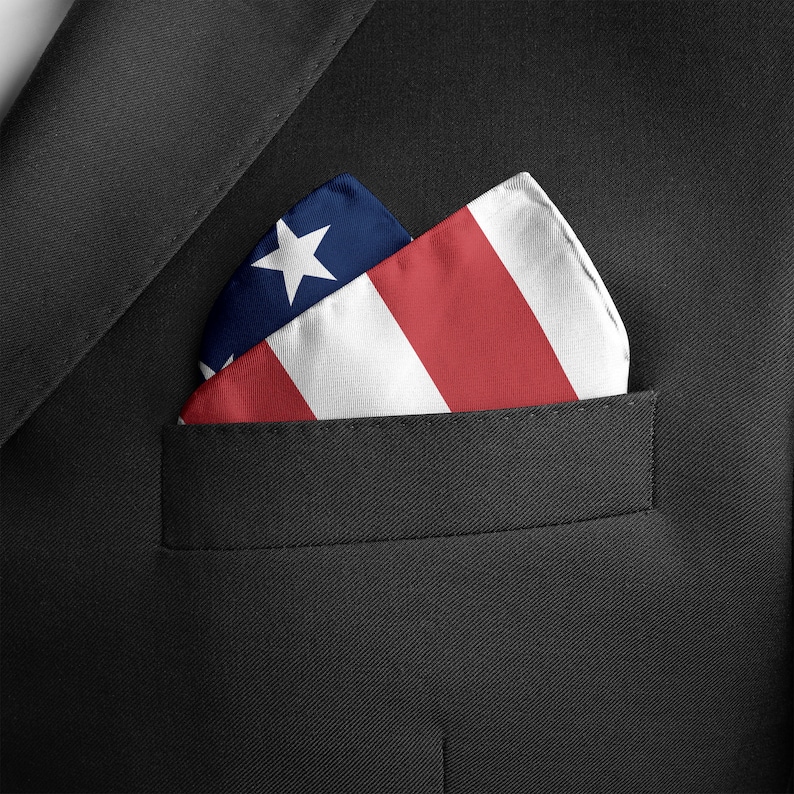 Puede incluir: Un pa&ntilde;uelo de bolsillo doblado con un dise&ntilde;o de bandera estadounidense roja, blanca y azul. El pa&ntilde;uelo de bolsillo est&aacute; en el bolsillo de la chaqueta de un traje.