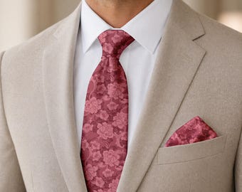 May include: A beige blazer worn over a crisp white shirt with a dark red necktie featuring a repeating floral pattern. A matching dark red floral pocket square is tucked into the breast pocket of the blazer, completing the formal ensemble.
