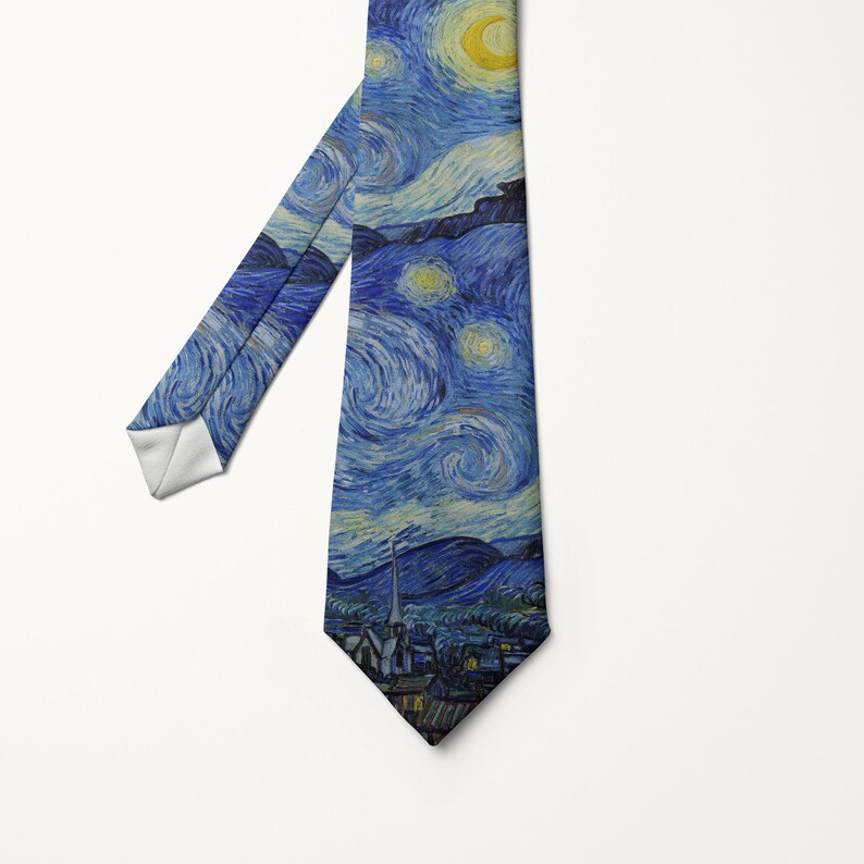 K&ouml;nnte beinhalten: Eine Krawatte mit dem Druck von Vincent van Goghs "Sternennacht". Die Krawatte zeigt den wirbelnden blauen und gelben Nachthimmel mit einem Mond und Sternen &uuml;ber einem Dorf. Die Krawatte hat ein wei&szlig;es Futter auf der R&uuml;ckseite.