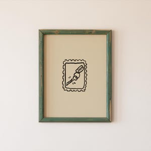 Puede incluir: Una impresión artística enmarcada con una ilustración en blanco y negro de una llave dentro de un diseño de sello postal. La llave tiene la palabra "CASA". El marco es de color verde desgastado.