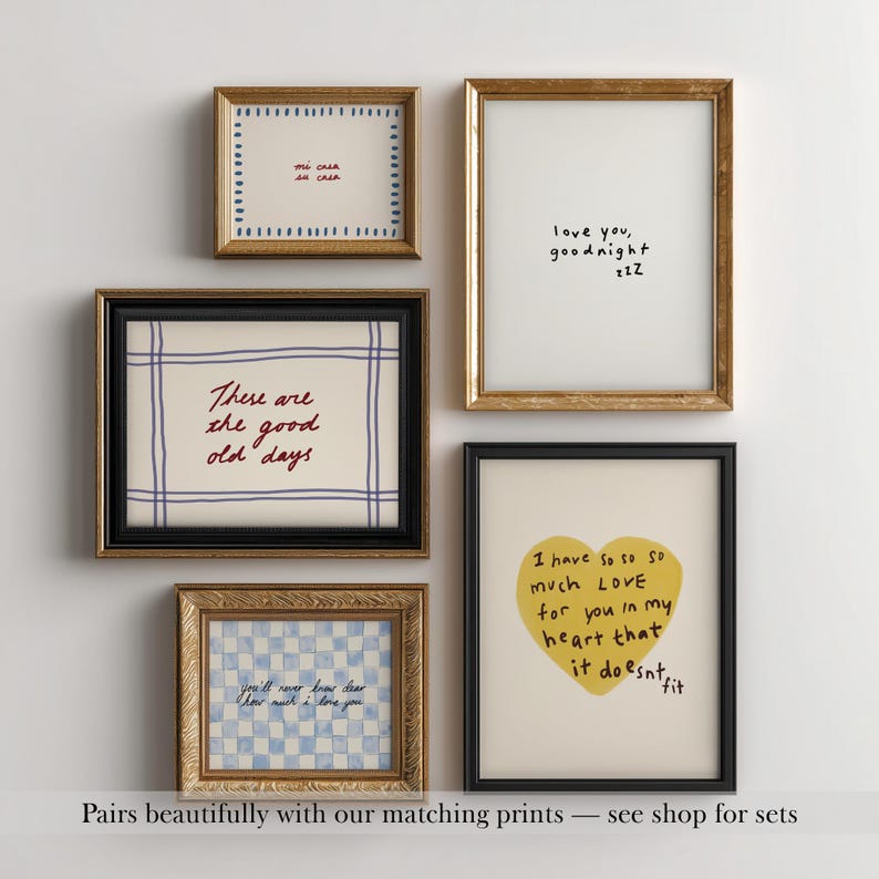May include: A collection of framed art prints with various designs and text. The prints feature gold and black frames. One print has a yellow heart with text, and others have handwritten phrases like "love you, goodnight".