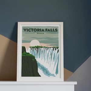 May include: A white framed poster with a vintage travel poster design featuring a depiction of Victoria Falls in Africa. The poster has the text "VICTORIA FALLS" and "AFRICA" in black.