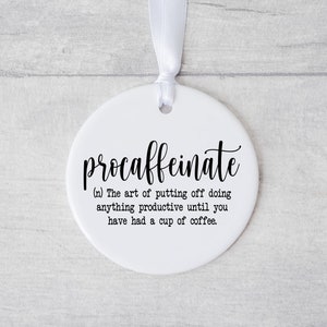 May include: White ceramic ornament with black text that reads "procaffeinate (n) The art of putting off doing anything productive until you have had a cup of coffee."