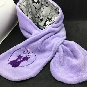 May include: Purple fleece scarf with a cat print lining and a purple embroidered design of two cats with hearts on the front.