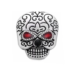 May include: Silver sugar skull charm with red eyes and black nose. The skull is decorated with intricate black floral designs.
