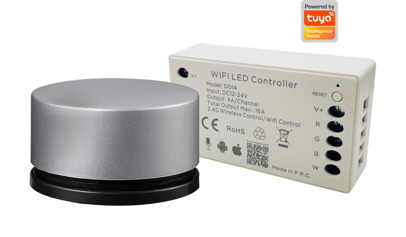Op de afbeelding: Een witte WiFi LED-controller met een zilveren afstandsbediening. De controller heeft een resetknop, een V+-aansluiting en vier uitgangskanalen met de labels R, G, B en W. De controller wordt aangedreven door Tuya Intelligence. De tekst op de controller luidt "WIFI LED Controller", "Model: D014", "Input: DC12-24V", "Output: 4A/Channel", "Total Output Max.: 16A", "2.4G Wireless Control/Wifi Control", "CE ROHS", "Made in P.R.C."