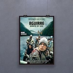 Può includere: Una locandina del film "Aguirre, furore di Dio" diretto da Werner Herzog. La locandina presenta un primo piano di Klaus Kinski nei panni di Aguirre, un conquistador, in una barca con altri uomini. La locandina è ambientata sullo sfondo di una lussureggiante giungla verde.