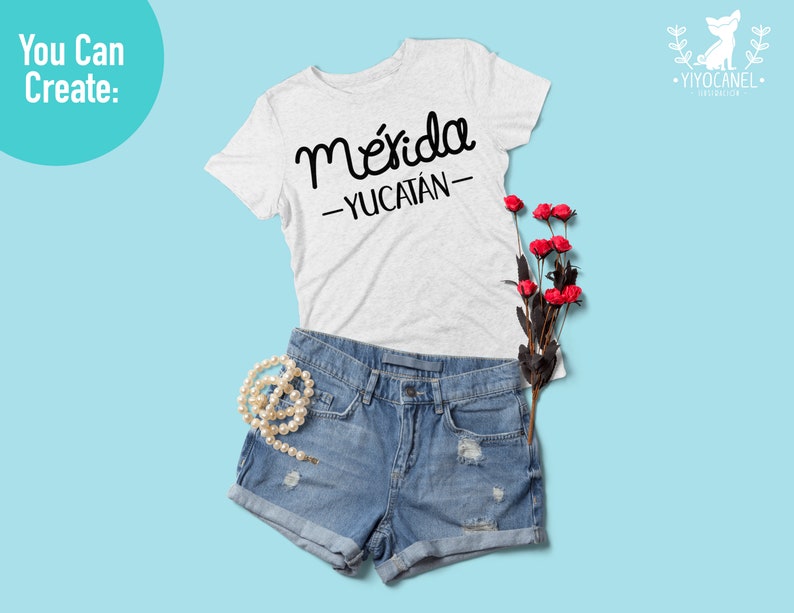 May include: A white t-shirt with the text "M&eacute;rida -YUCAT&Aacute;N- " in black lettering. The shirt is laid out on a light blue background with a pair of blue denim shorts, a pearl necklace, and a bouquet of red roses.